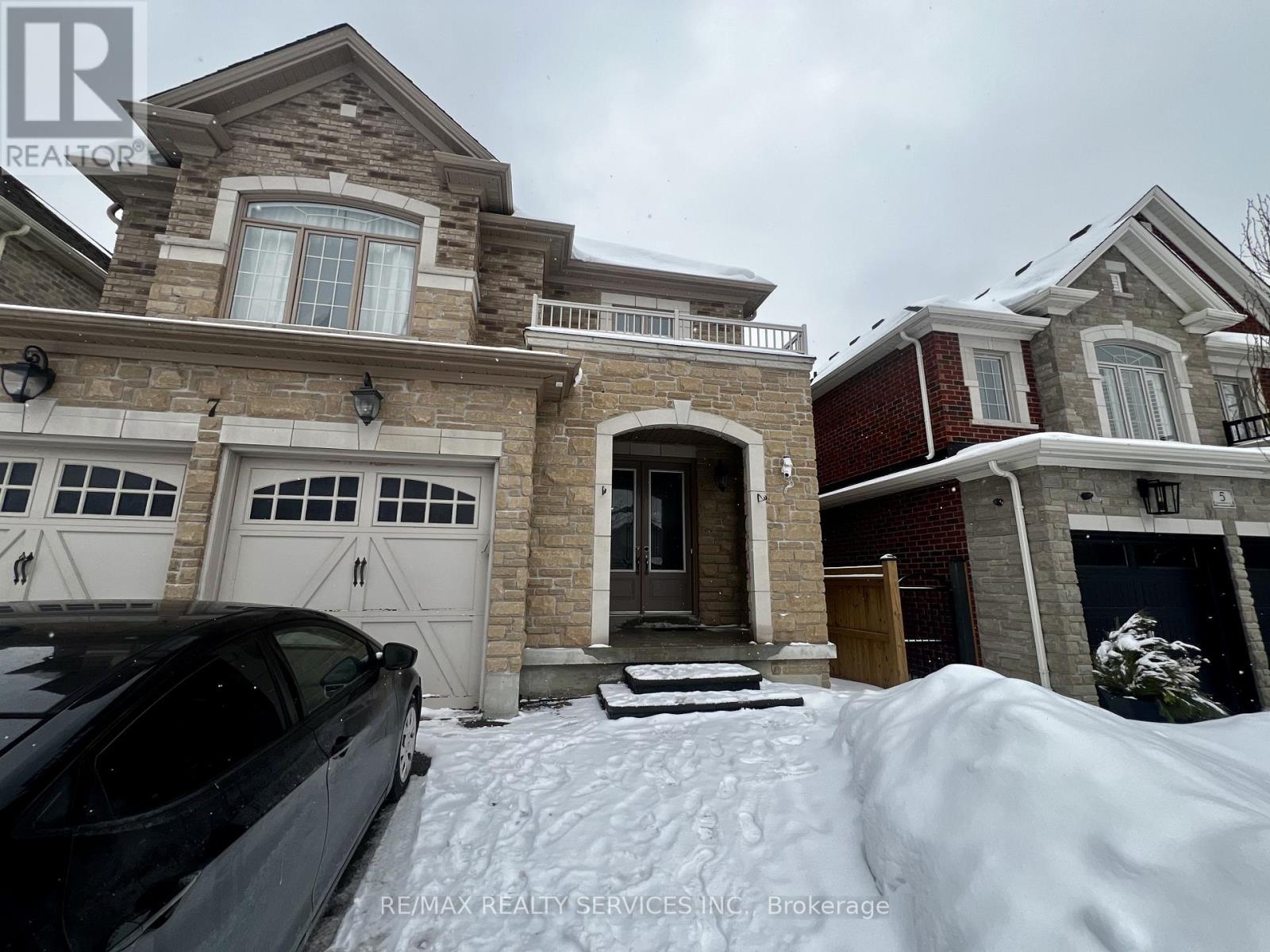 A black car is parked in front of a house with a snow-covered front yard.