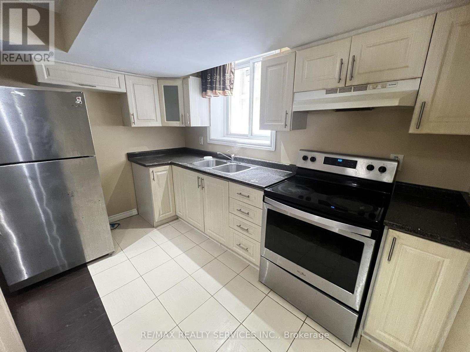 A kitchen with white cabinets and black countertops.