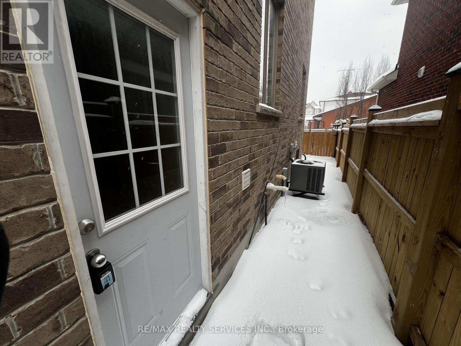A snow-covered walkway leads to a white door with a black handle.