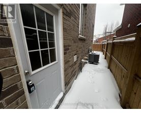 A snow-covered walkway leads to a white door with a black handle.