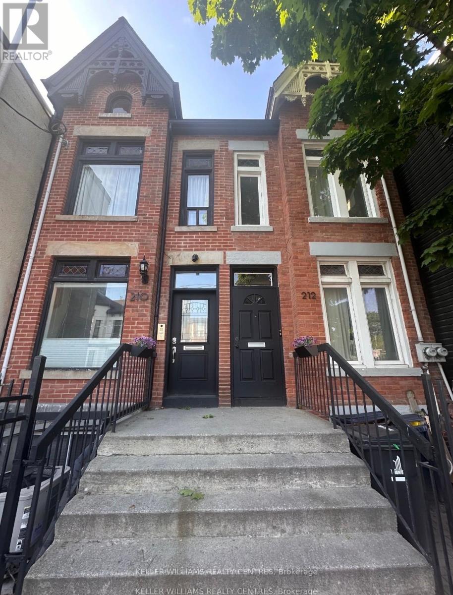 A brick house with a black front door and steps leading to the entrance.