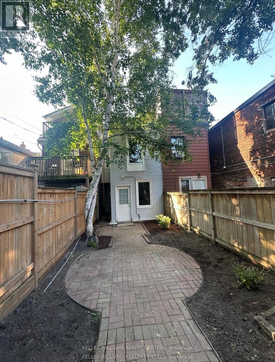 A backyard with a circular brick patio and a white door.