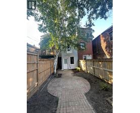 A backyard with a circular brick patio and a white door.