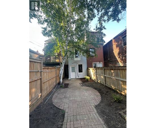 A backyard with a circular brick patio and a white door.