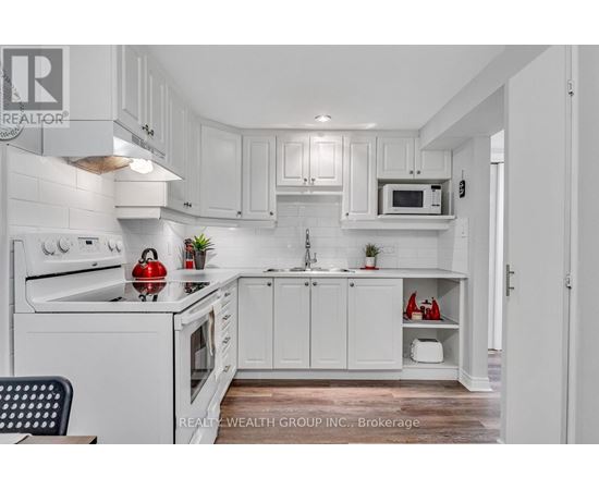 A white kitchen with a red apple on the stove.