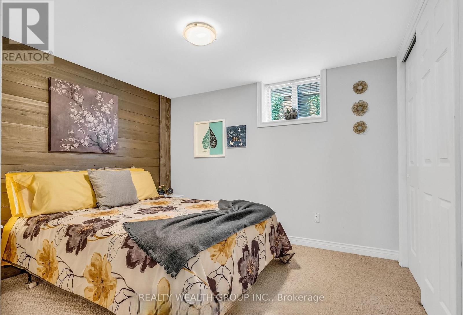 A bedroom with a floral bedspread and a window with a view of trees.