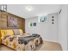 A bedroom with a floral bedspread and a window with a view of trees.