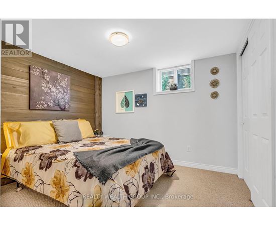 A bedroom with a floral bedspread and a window with a view of trees.