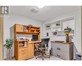 A well-organized office space with a wooden desk, chair, and shelving unit.