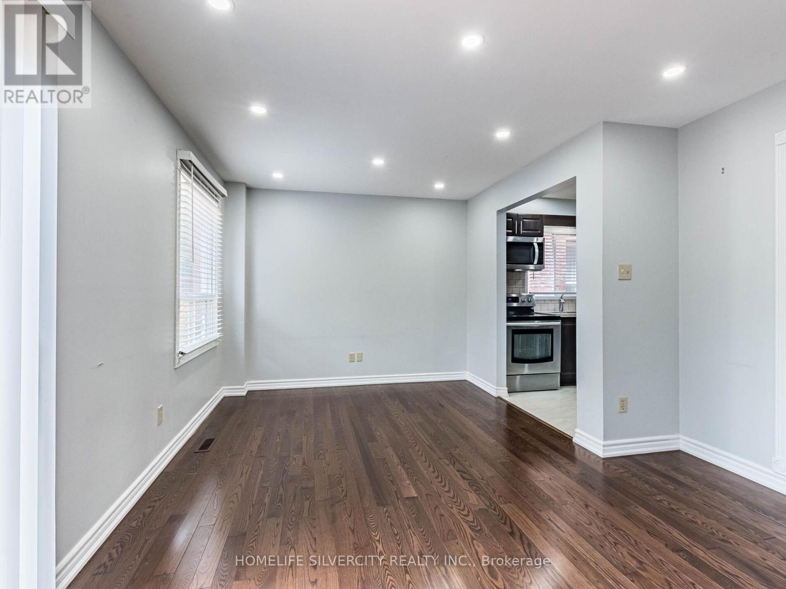 A spacious room with wooden flooring and white walls.