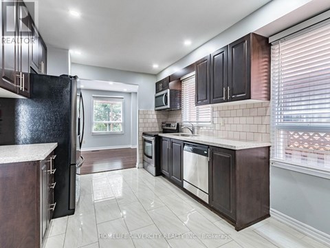 A modern kitchen with dark wood cabinets and white appliances.