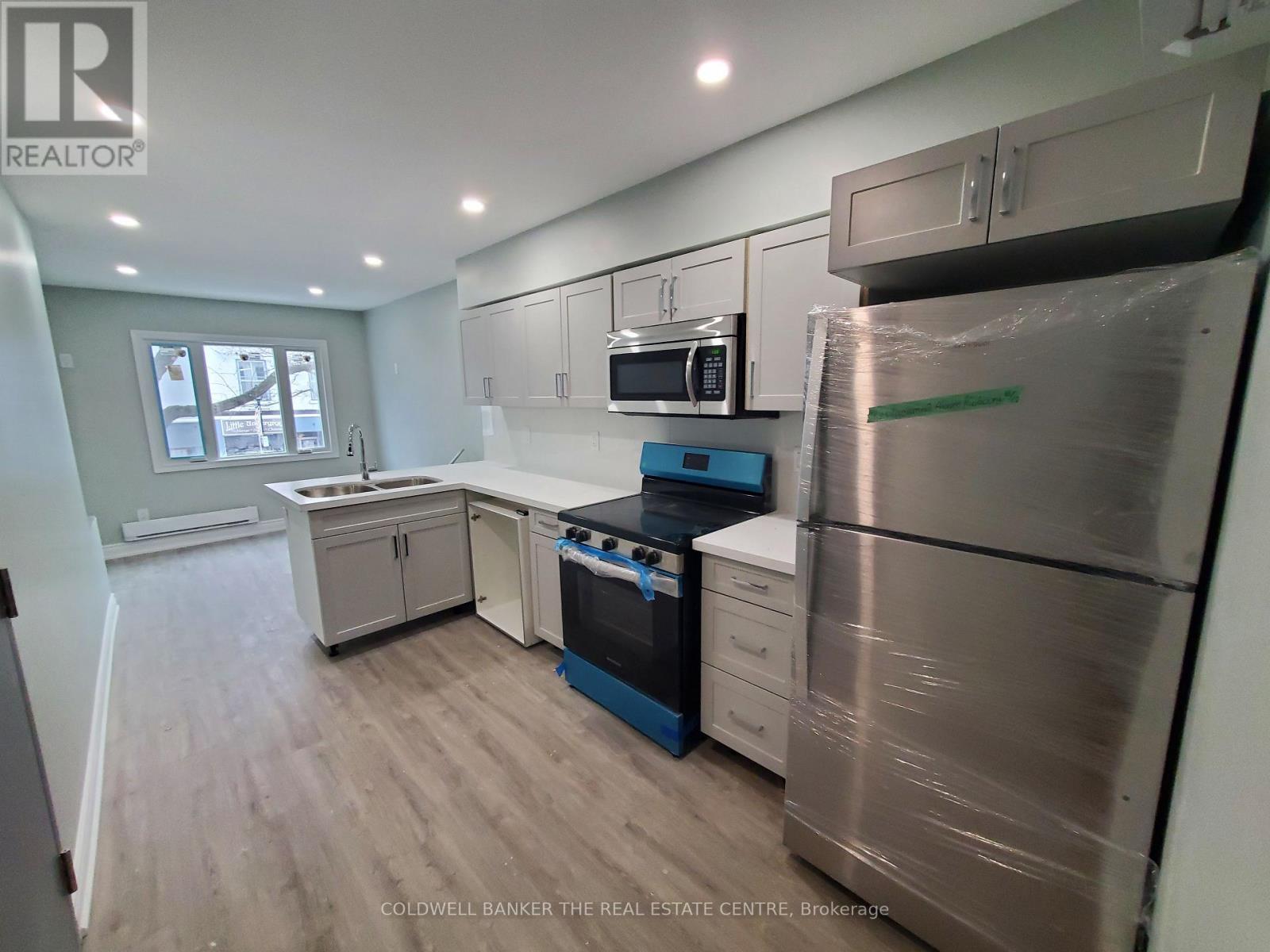 A kitchen with a refrigerator, oven, and microwave.