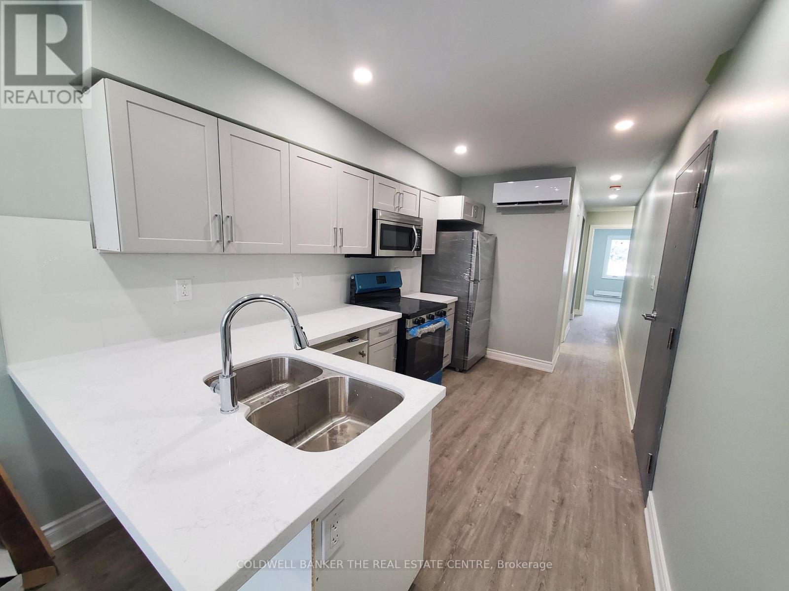 A kitchen with white countertops and stainless steel appliances.
