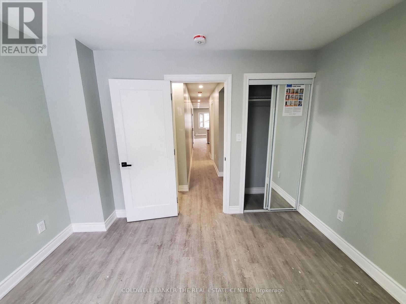 A hallway with a white door and a glass door leading to another room.