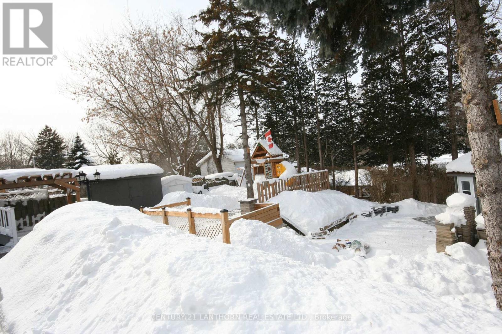 A snow-covered landscape with a cabin and trees in the background.
