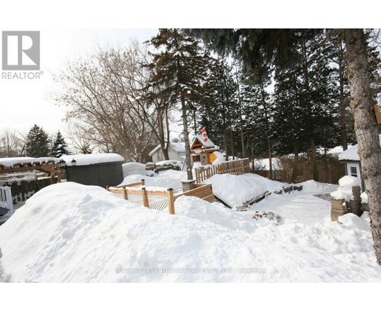 A snow-covered landscape with a cabin and trees in the background.