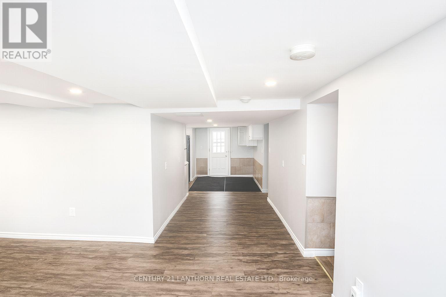 A spacious room with wooden flooring and white walls.