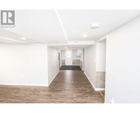 A spacious room with wooden flooring and white walls.