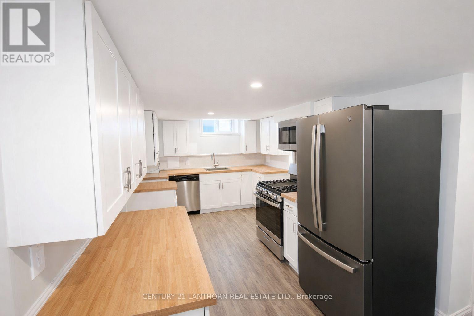 A kitchen with a black fridge and white cabinets.