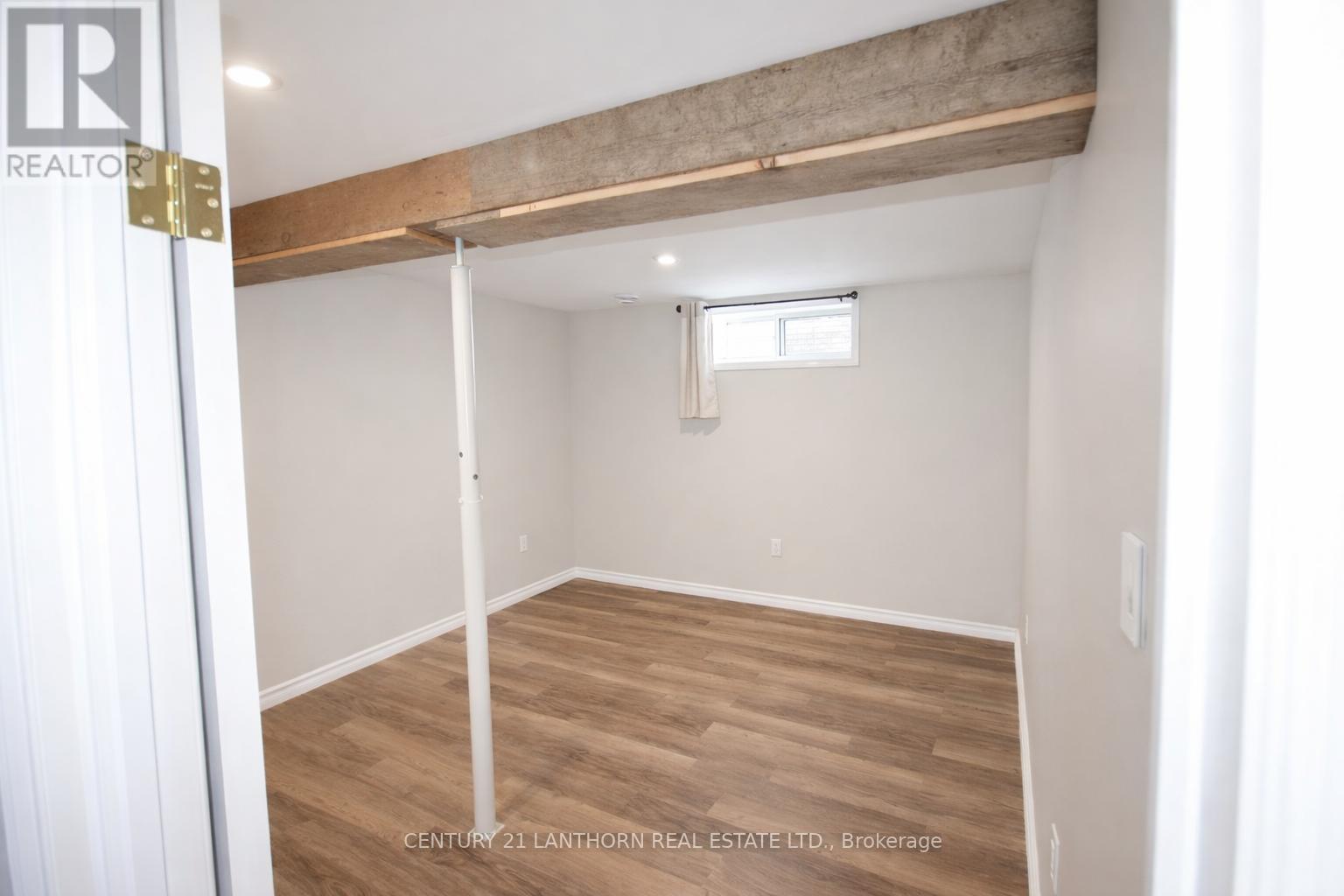 A room with a window and a wooden beam on the ceiling.