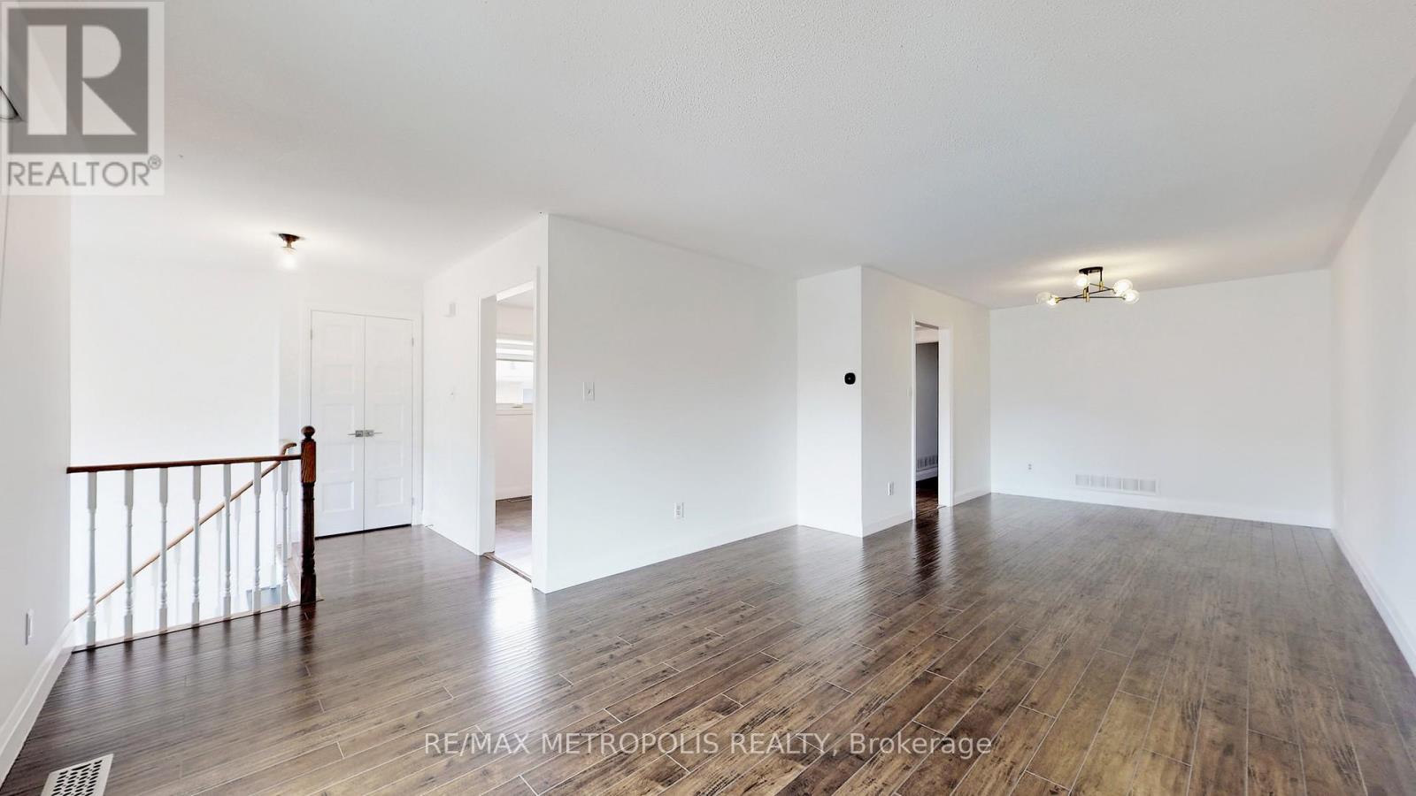 A spacious room with wooden flooring and white walls.