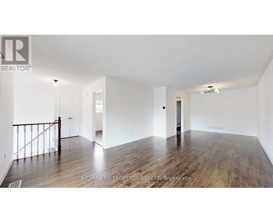 A spacious room with wooden flooring and white walls.