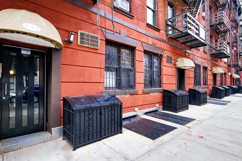 the side of a building with a sidewalk and trash cans
