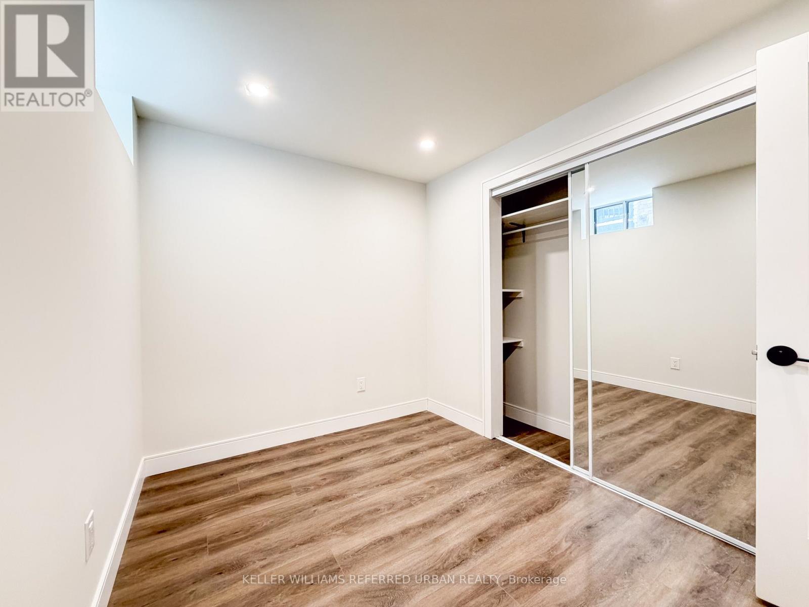 A bedroom with a bed, nightstand, and a mirror on the wall.