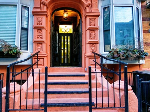 the front door of a house with steps and a black gate