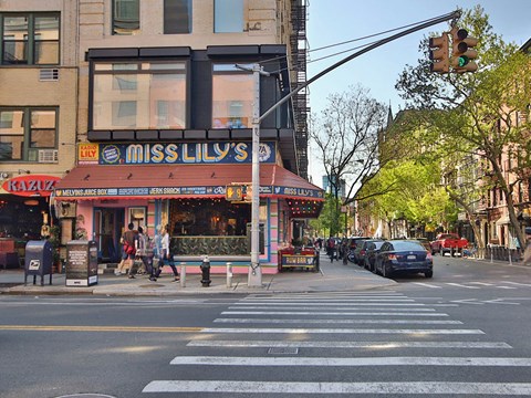 a busy city street with pedestrians and a restaurant on the corner