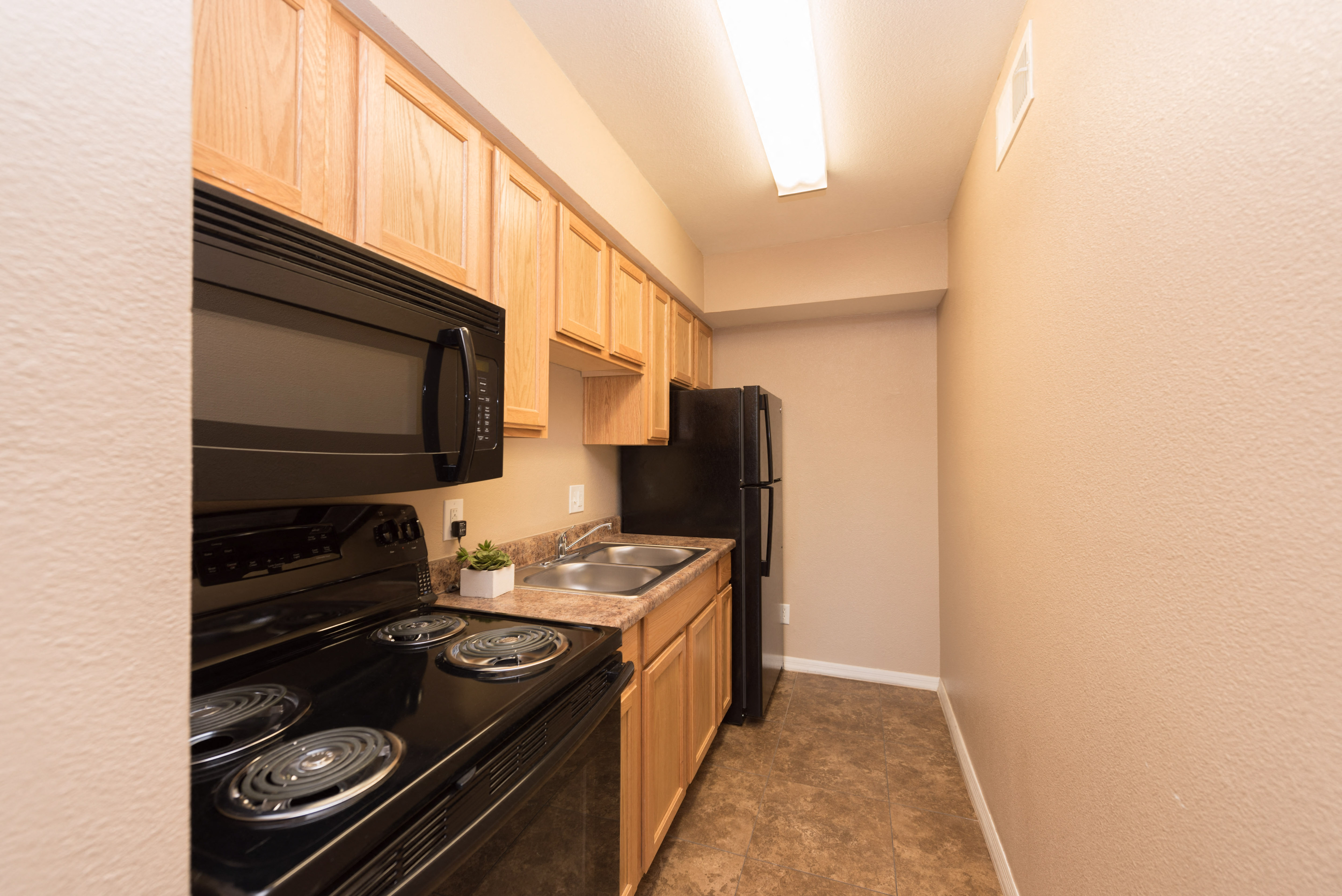 redesigned kitchen with black appliances and wood cabinets and a black refrigerator