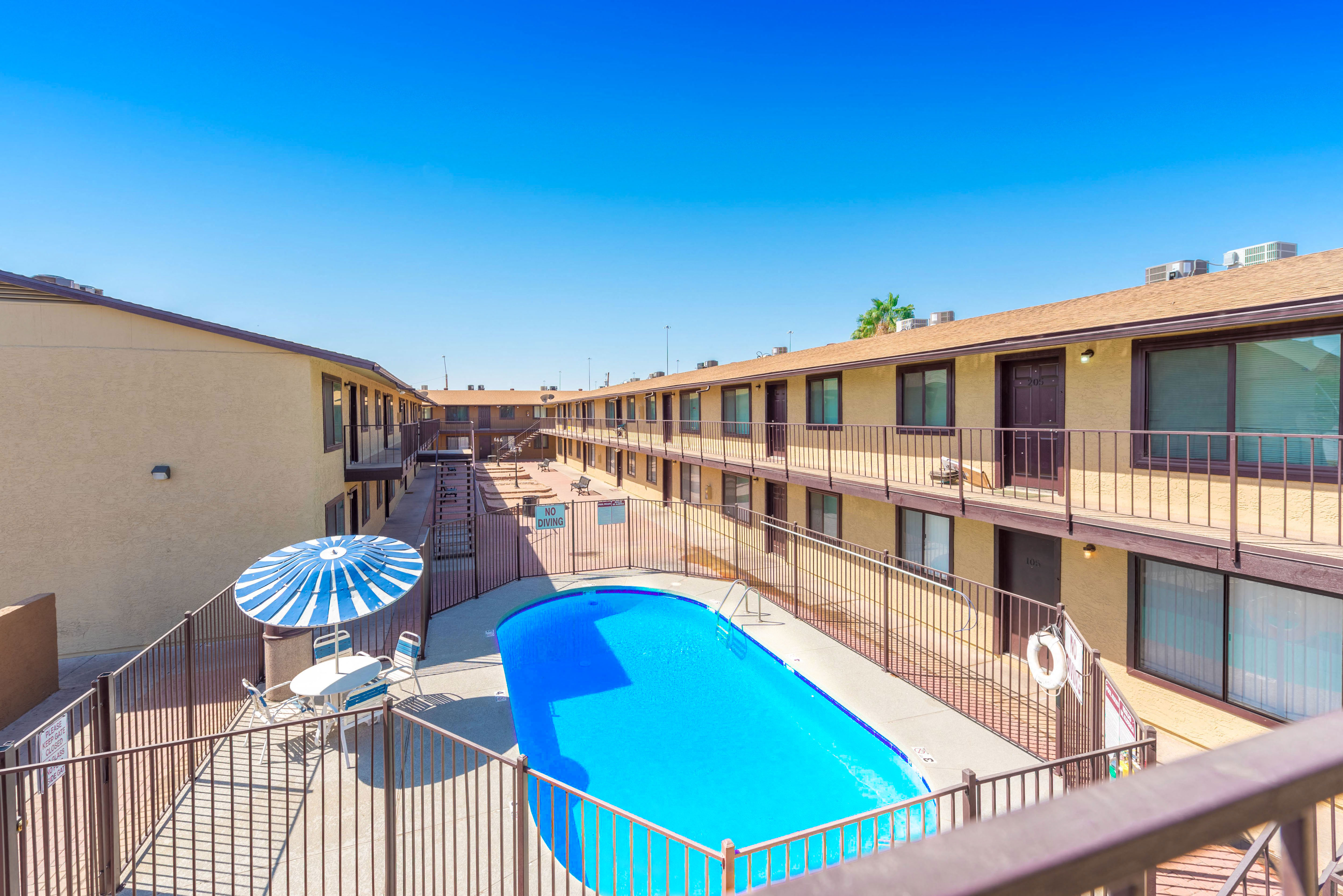a view of a pool and a building with a blue umbrella