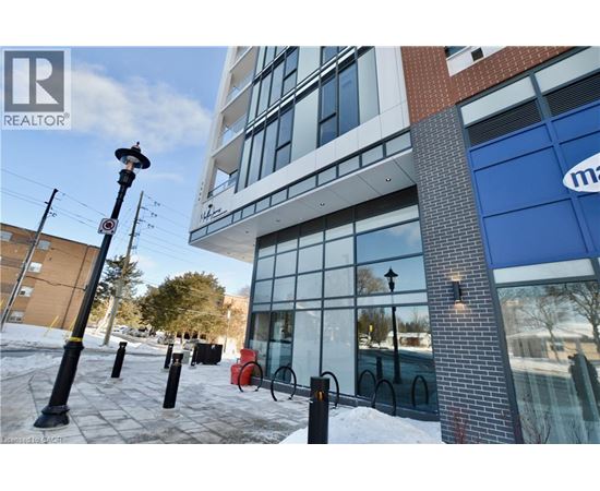 A building with a blue sign on the right side and a red bike rack in front of it.
