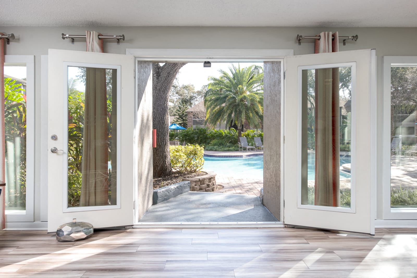 a view of a pool from a house with open doors