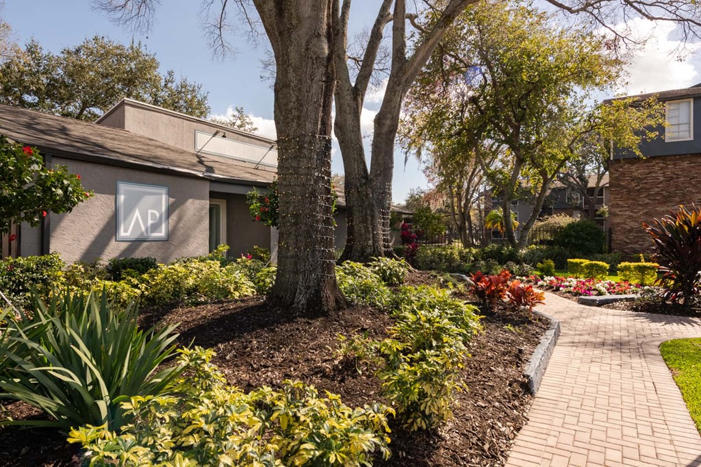 a walkway through a garden in front of a house
