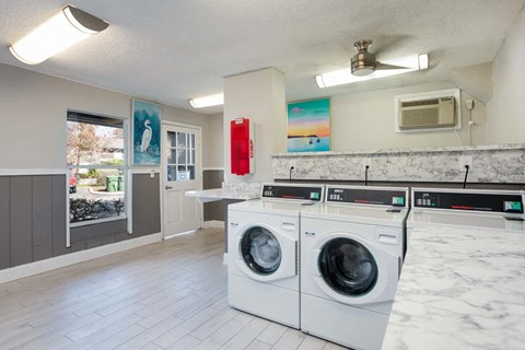 a laundry room with two washing machines and a counter with a window