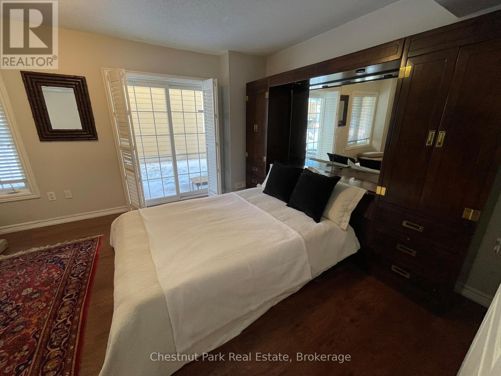 A bedroom with a white bed and a red rug.