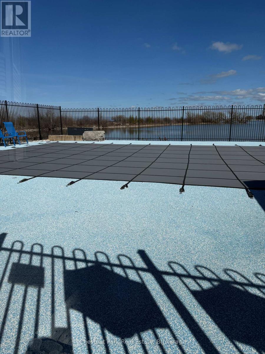 A pool with a black fence and a blue chair.