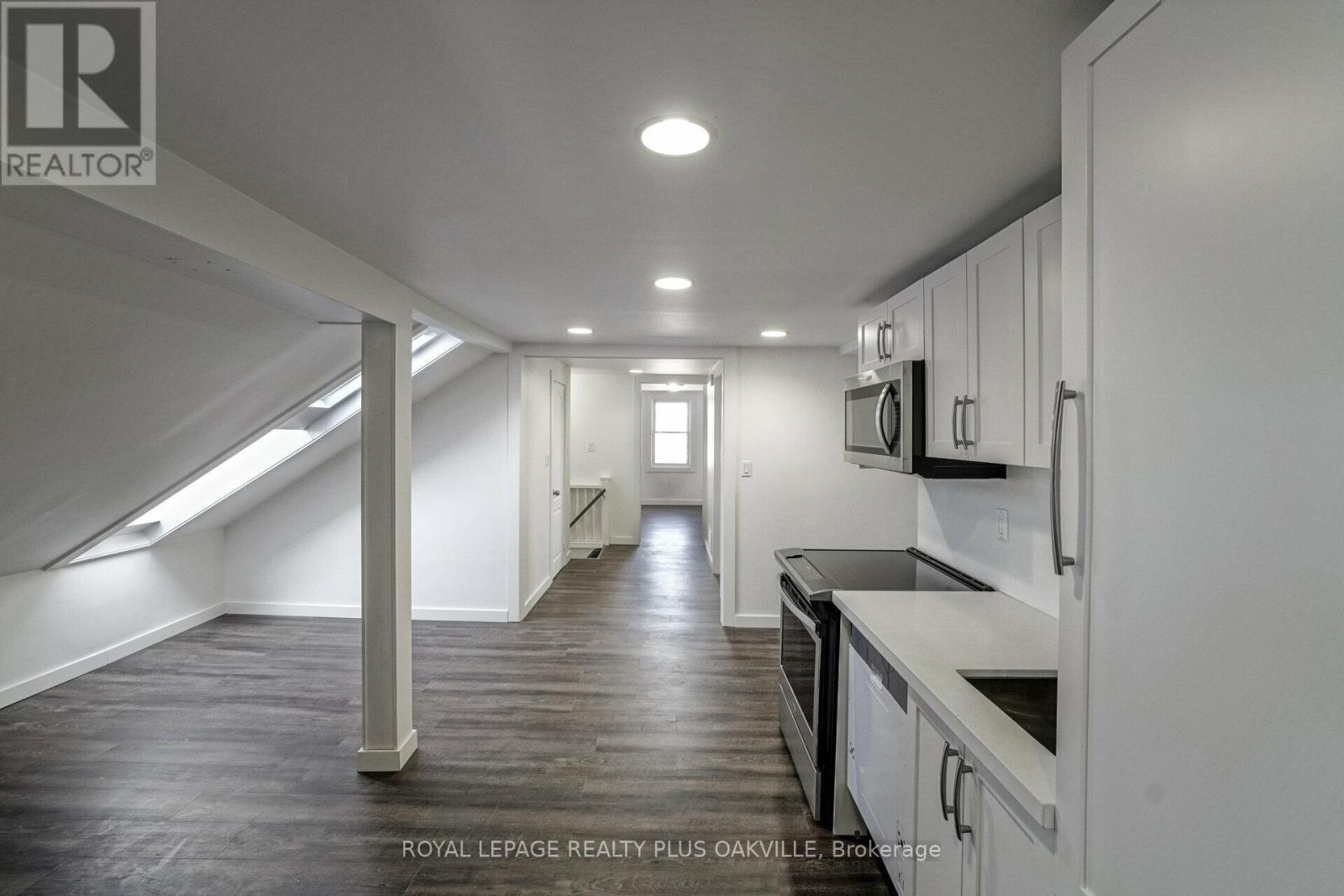A spacious kitchen with white cabinets and black countertops.