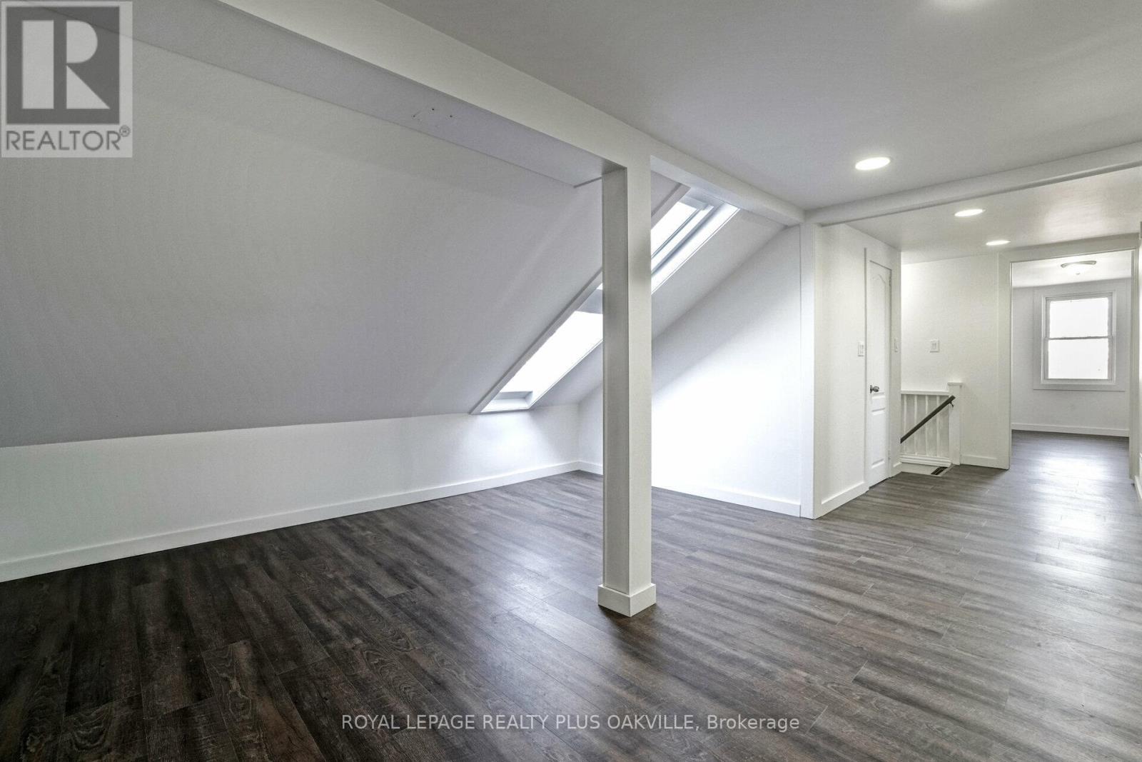 A room with wooden floors and white walls, with a skylight above.
