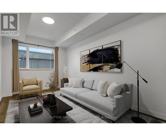 A modern living room with a grey sofa, a coffee table, and a large abstract painting on the wall.