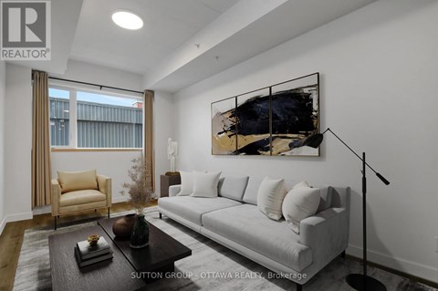 A modern living room with a grey sofa, a coffee table, and a large abstract painting on the wall.
