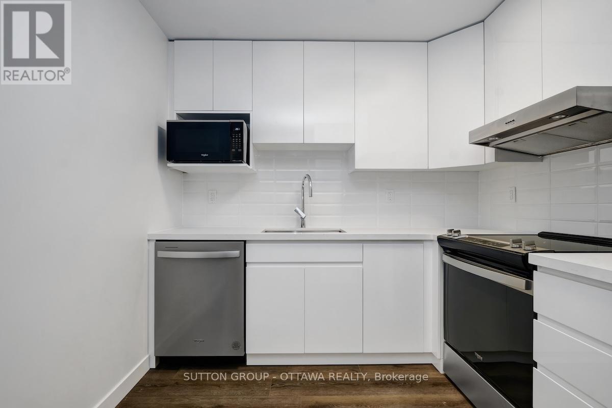 A kitchen with white cabinets and a black microwave.