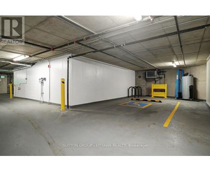 A large, empty warehouse space with a white wall and yellow safety lines on the floor.