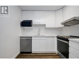 A kitchen with white cabinets and a black microwave.