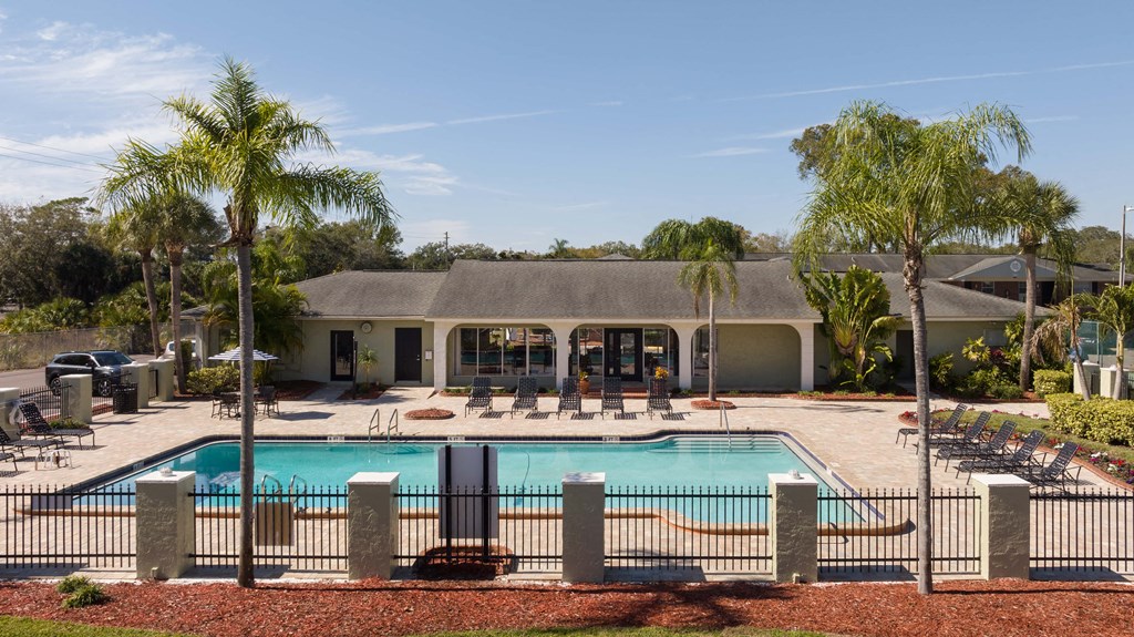 a swimming pool in front of a house with palm trees