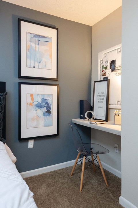 a bedroom with a desk and two pictures on the wall
