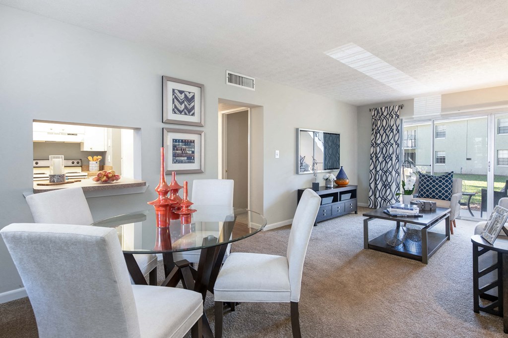 a dining room and living room with a glass table and white chairs