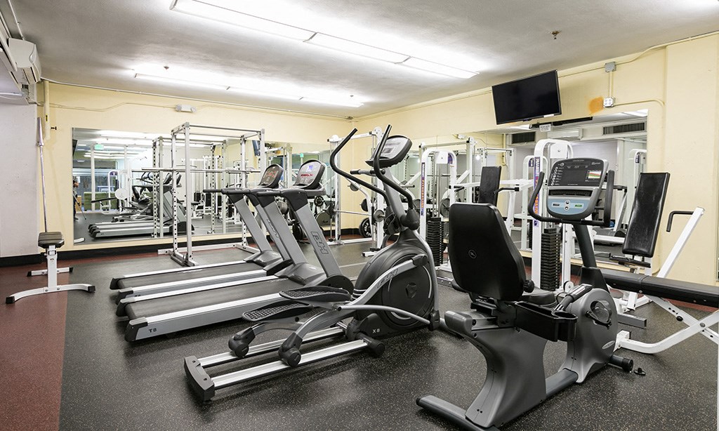 a gym with cardio equipment and weights on the floor