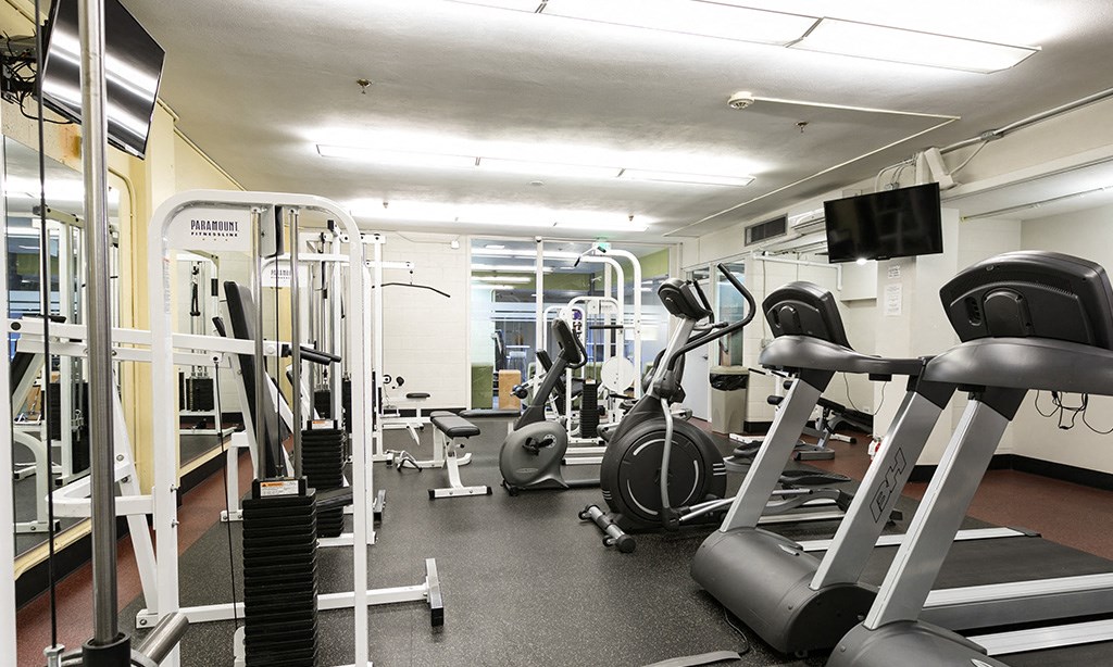a gym with cardio equipment and weights on the floor